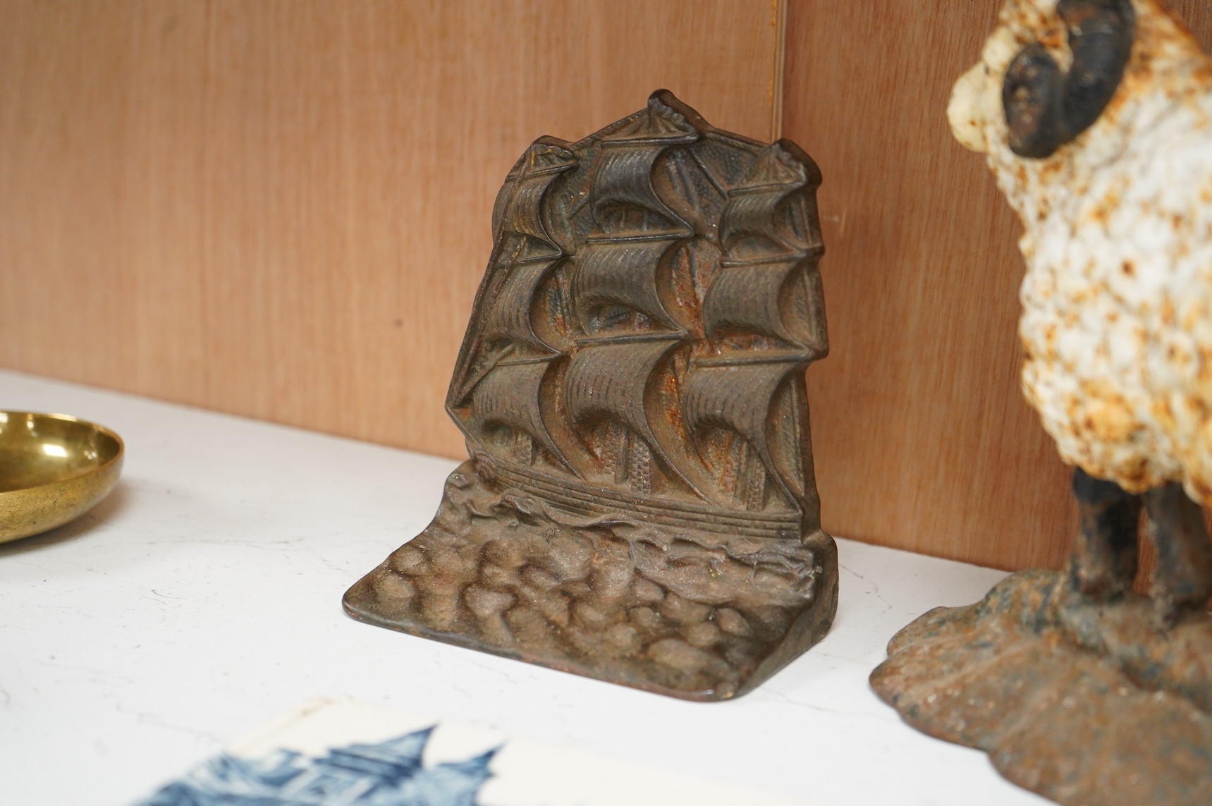 A Minton blue and white tile and two cast iron door stops, one in the form of a sheep, 24cm wide